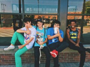 alt =" four teenage boys sitting and relaxing on the wall"'